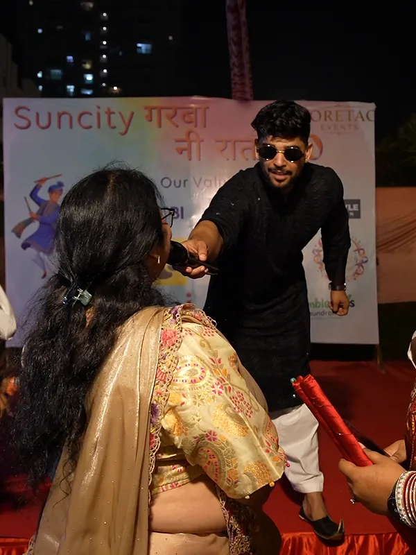 Ashish hands the mic to a guest on the red stage at Suncity Garba Ni Raat 2.0